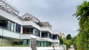 A modern residential building with multiple balconies, large windows, and a pathway lined with greenery. - Le Paradis Penthouse Apartment (Hermanus)