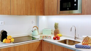 Eine moderne Küche mit Holzausstattung, einer Edelstahl-Mikrowelle, einem Toaster und einem Spülbecken.