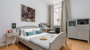 Un dormitorio ordenado con cama, mesitas de noche, cómoda y ventana con cortinas.