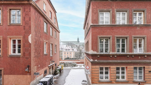 Una calle estrecha bordeada de edificios de ladrillo rojo con nieve en el suelo.