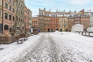 Une rue pavée bordée de bâtiments historiques, de bancs et recouverte de neige.