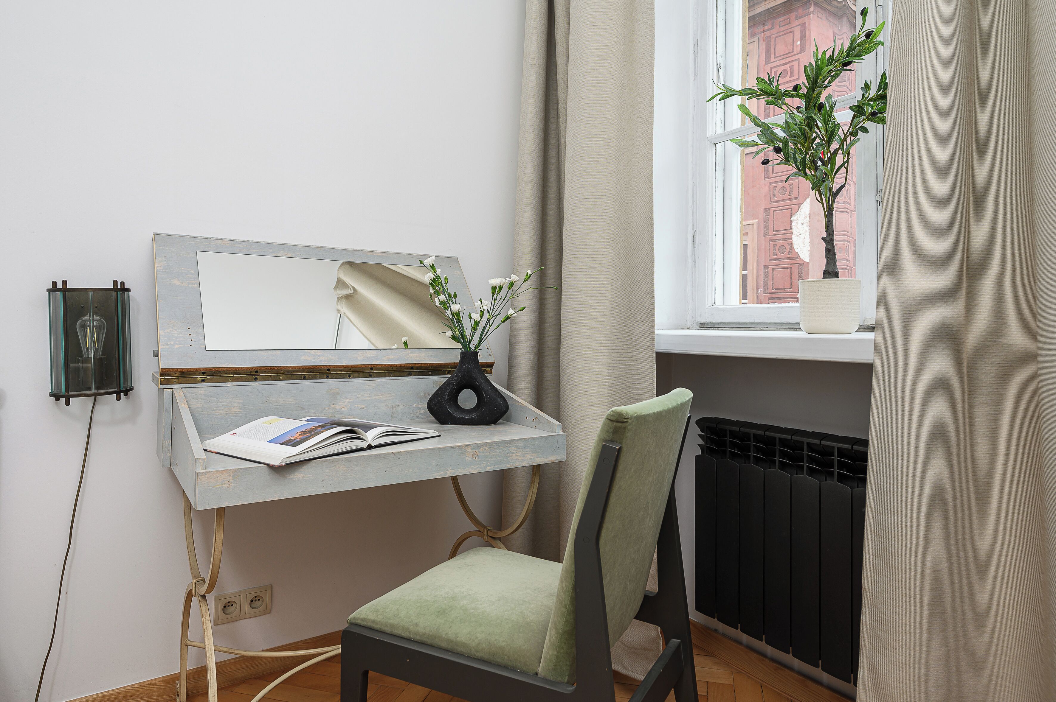 A small workspace with a desk, chair, and a potted plant by a window.