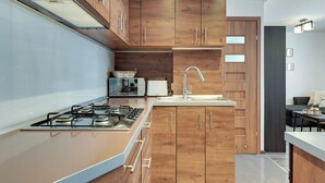 Une cuisine moderne avec des meubles en bois, une cuisinière à gaz, un évier et un grille-pain.