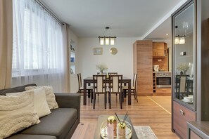 A modern living room with a sofa, dining table, and kitchen area. - Piastowska near the Jelitkowo Beach & Reagan Park by Downtown Apartments (Gdańsk)