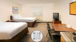 Una habitación de hotel con dos camas, un escritorio, un televisor y una ventana.