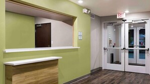 Un espace d’accueil avec un comptoir en bois, un mur végétal et une porte de sortie.