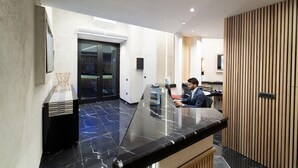 A modern reception area with a marble floor, a reception desk, and a wooden panel wall. - Naples Royal House B&B (Naples)