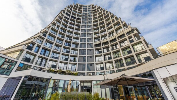Um edifício moderno alto com fachada curva, várias varandas e grandes janelas.