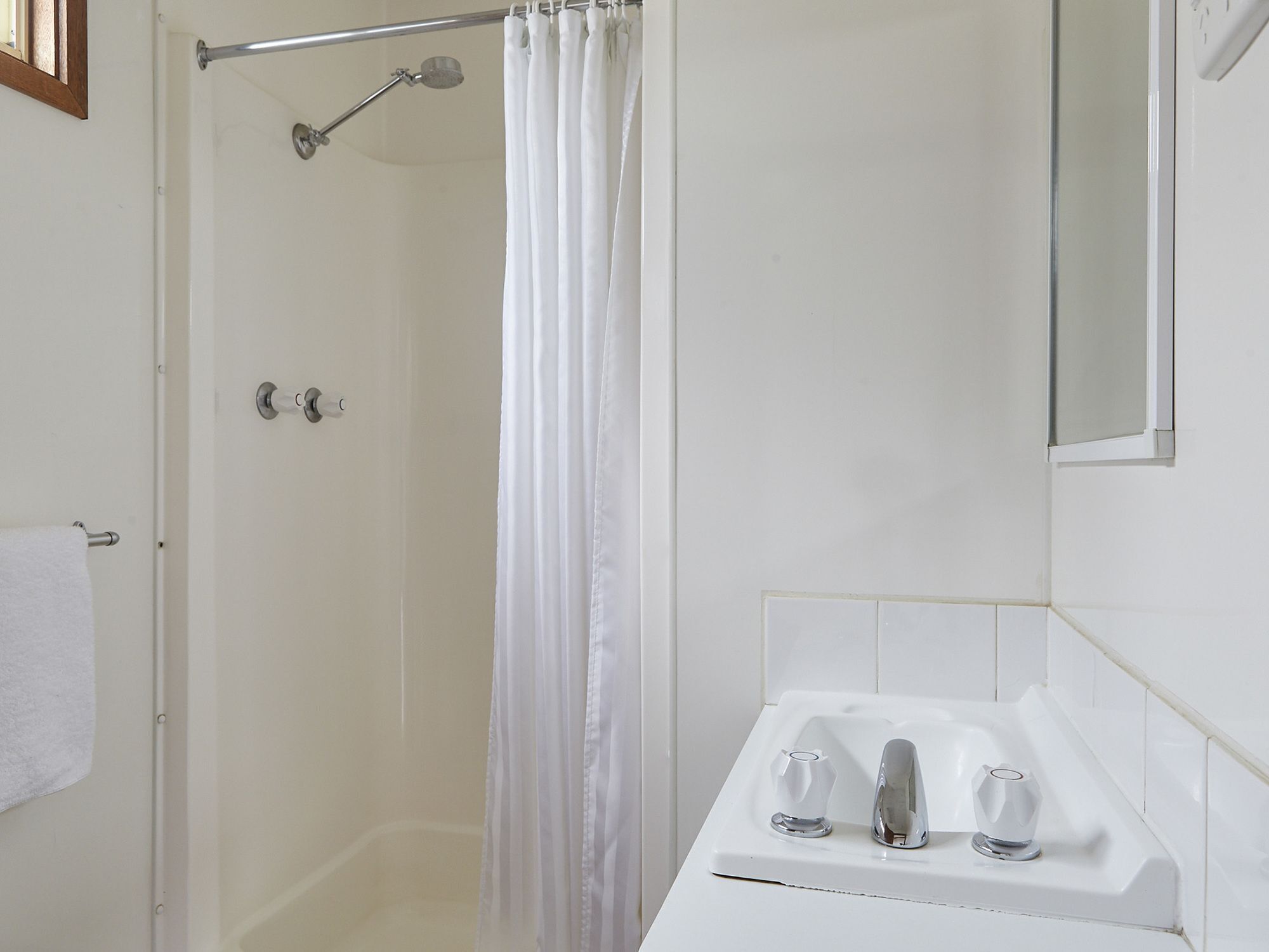 A bathroom with a shower, a toilet, and a sink with two faucets.