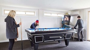 Une table de billard dans une pièce dotée de deux fenêtres et d’un appareil de climatisation.