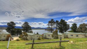 Une propriété au bord du lac comprenant plusieurs chalets, une clôture en bois et une vue dégagée sur le lac et les montagnes en arrière-plan.