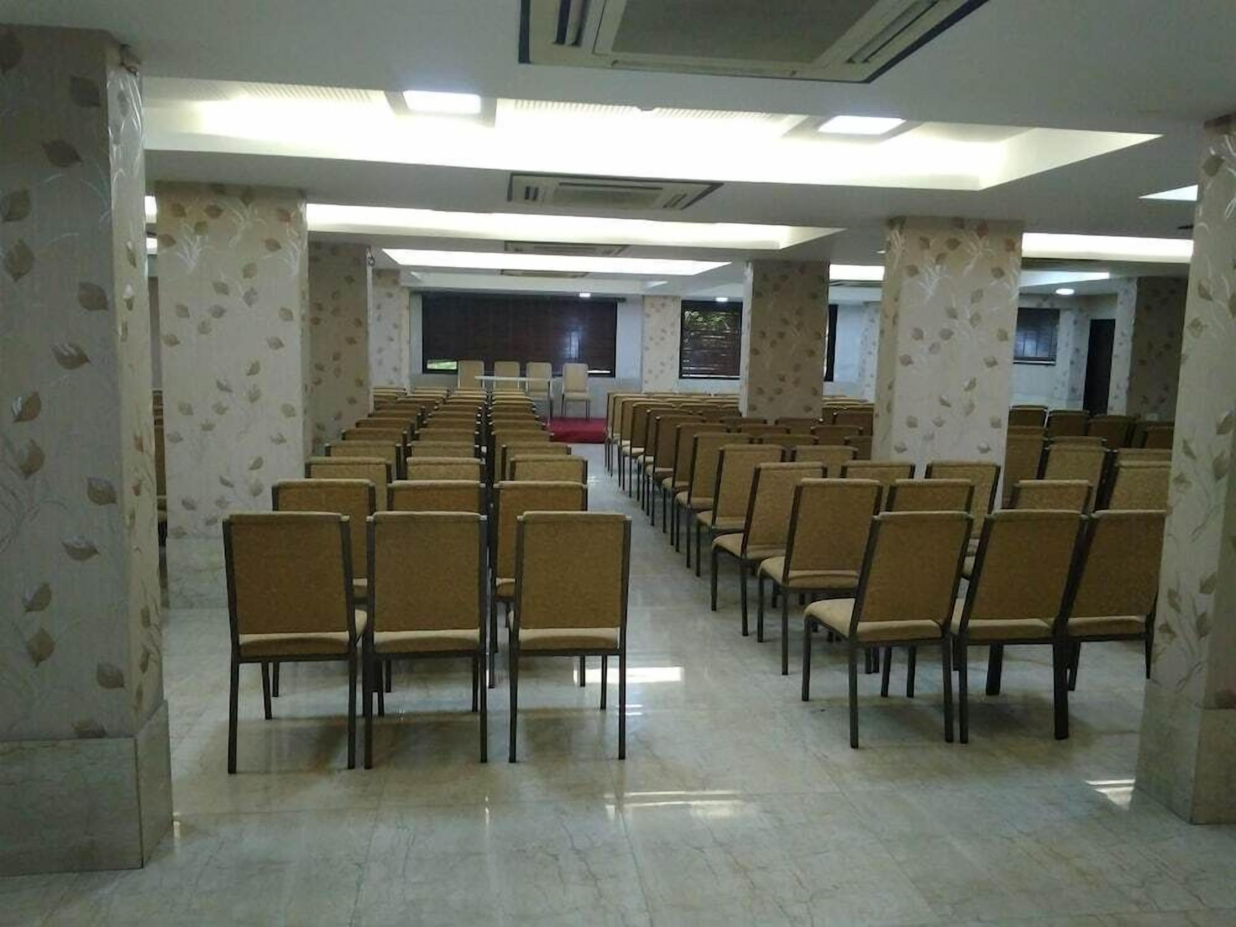 A conference room with rows of chairs, a stage, and a projector screen.