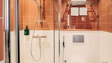Un baño moderno con cabina de ducha de vidrio, un perchero con toallas dobladas y un estante con artículos de tocador.