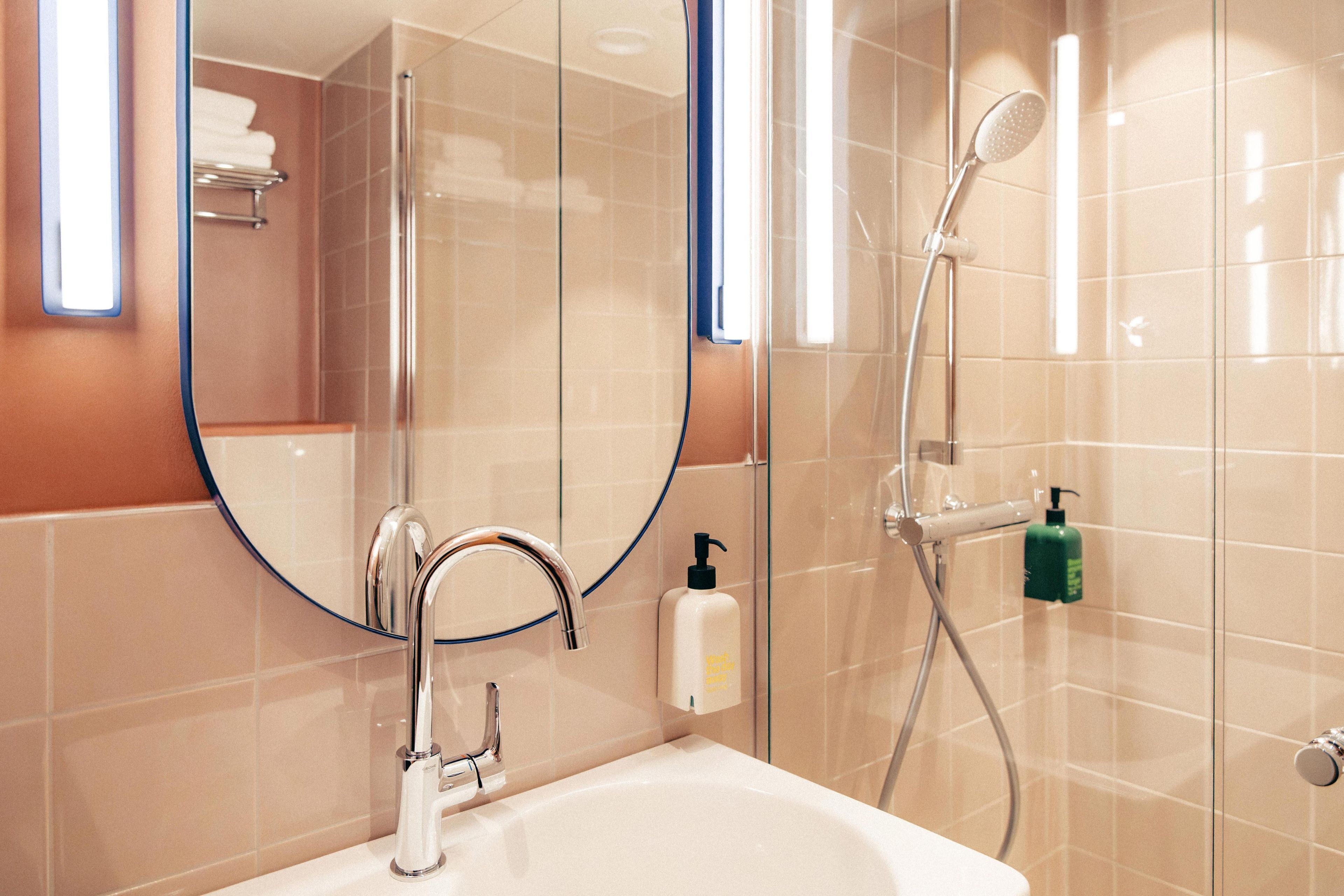 Une salle de bain équipée d’un lavabo, d’un miroir, d’une douche et d’articles de toilette.