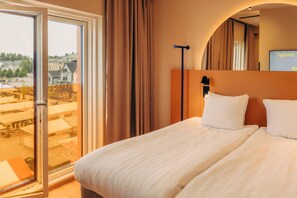 Una habitación de hotel con una cama, un ventanal y vistas a edificios.