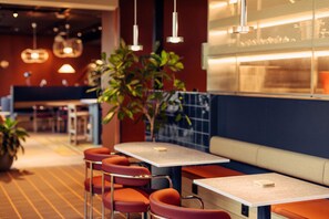 Un interior de restaurante con cabinas, mesas y luces colgantes.