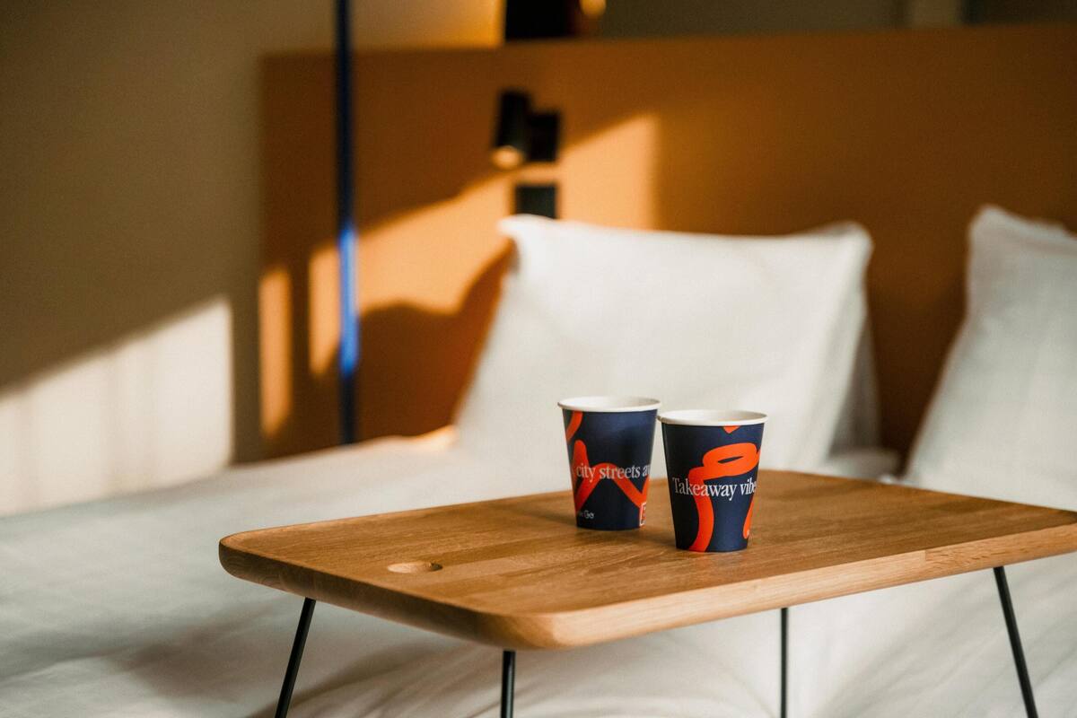 A wooden table with two cups on a bed.