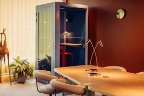 Una sala de reuniones moderna con una mesa, sillas, una lámpara y un reloj en la pared.