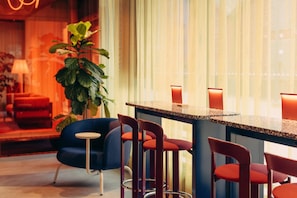 A modern bar area with a bar counter, red chairs, and a potted plant. - Scandic Go, Saaristonkatu 1 (Oulu)