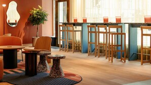 A modern interior with wooden chairs, a round table, a small potted plant, and a mirror on the wall. - Scandic Go, Saaristonkatu 1 (Oulu)