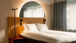 A modern hotel room with a large bed, a bedside table with a lamp, and a large window with curtains. - Scandic Go, Saaristonkatu 1 (Oulu)