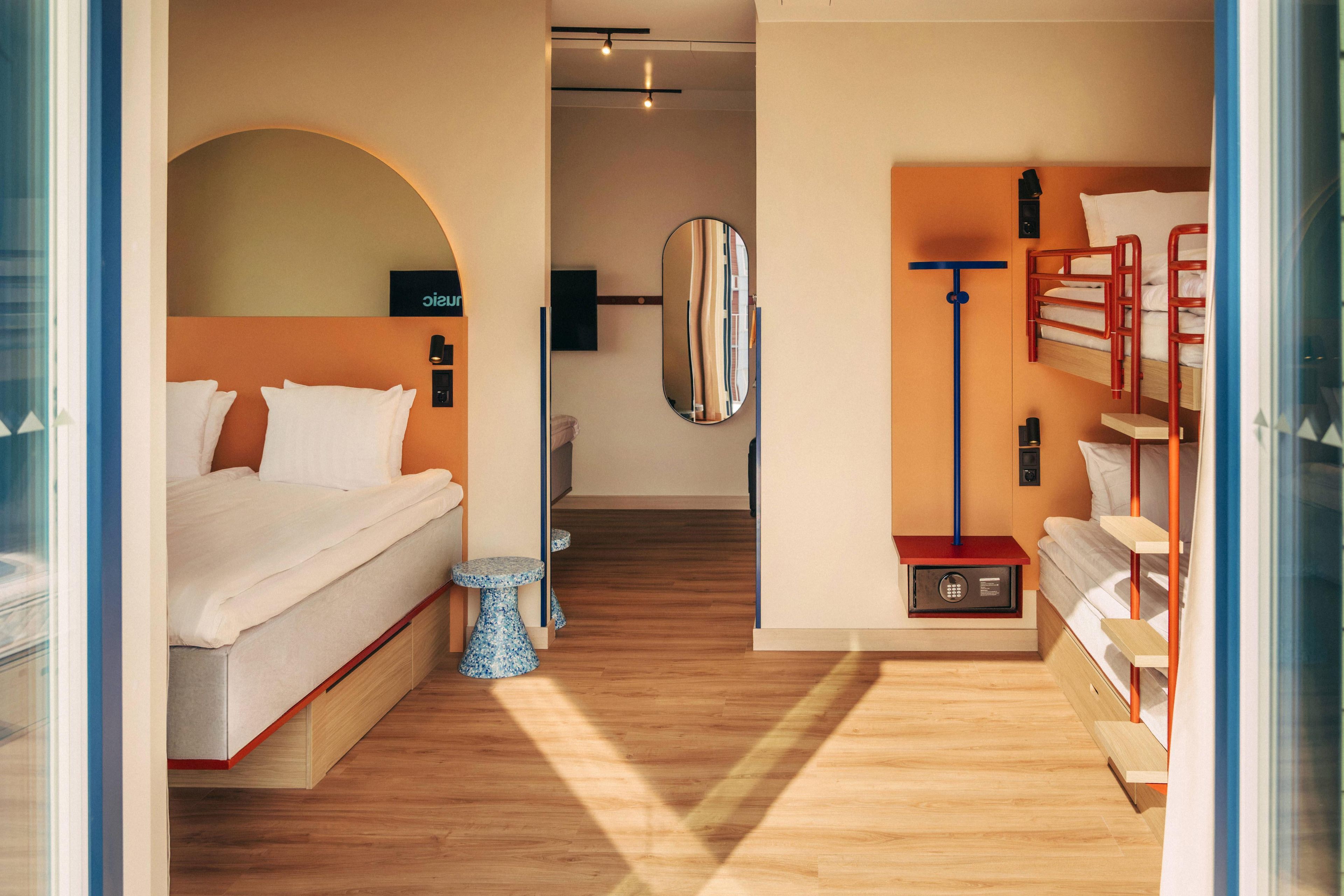 Une chambre d’hôtel moderne avec un lit, une petite table, un miroir et une échelle rouge.