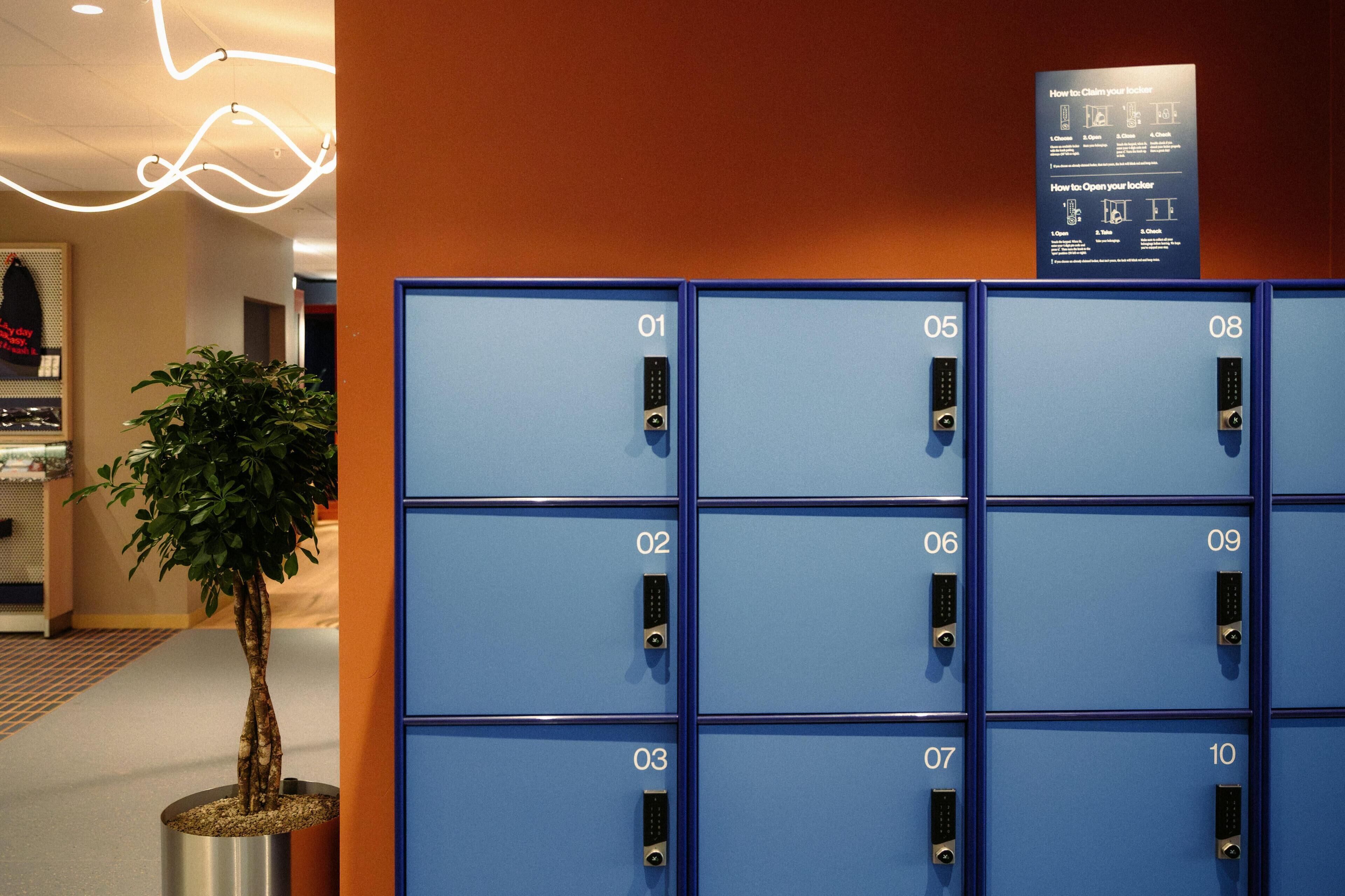 A row of blue lockers numbered 01 to 10, with a sign above detailing locker usage instructions.