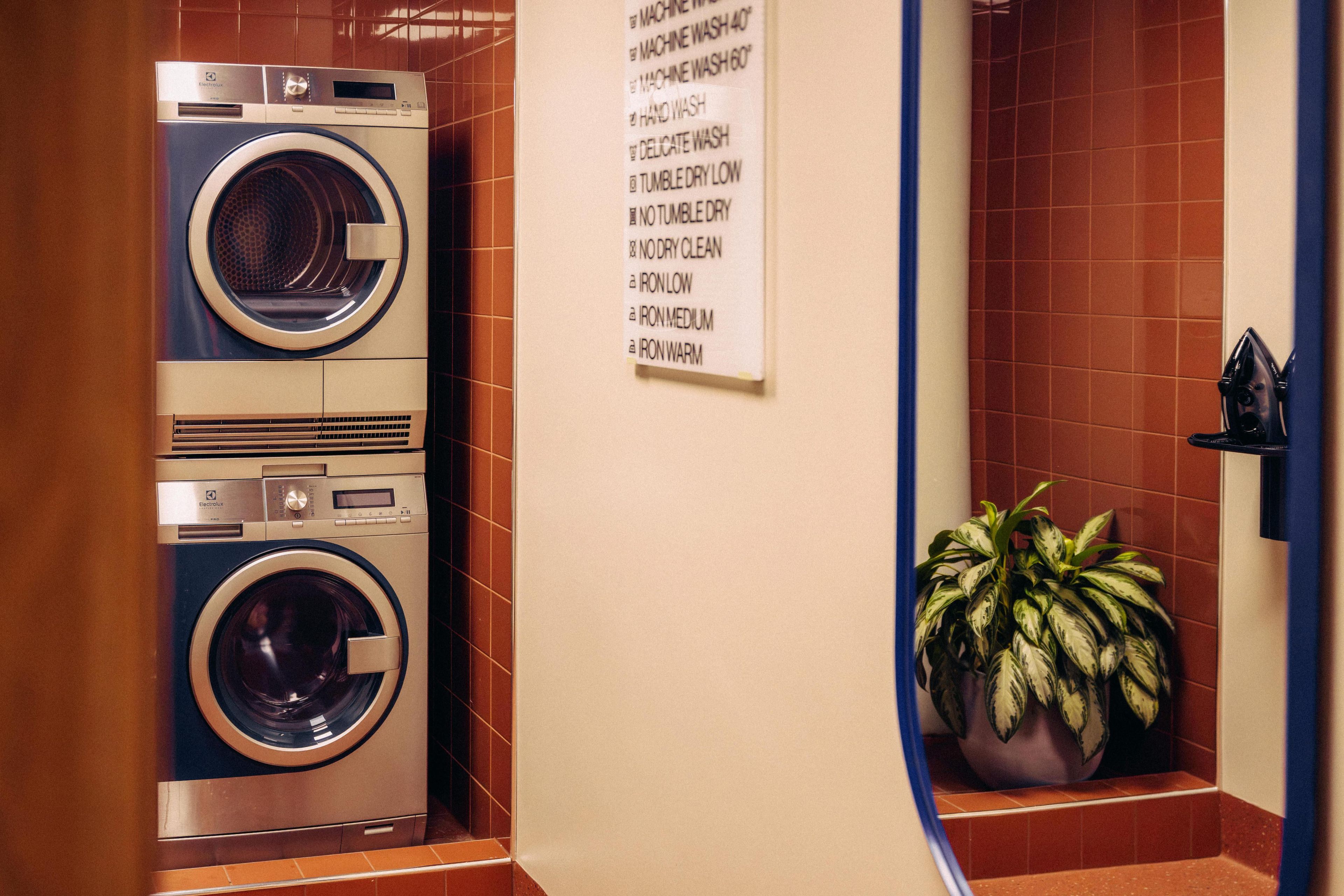A laundry room with two stacked washing machines and a wall-mounted instruction sign.