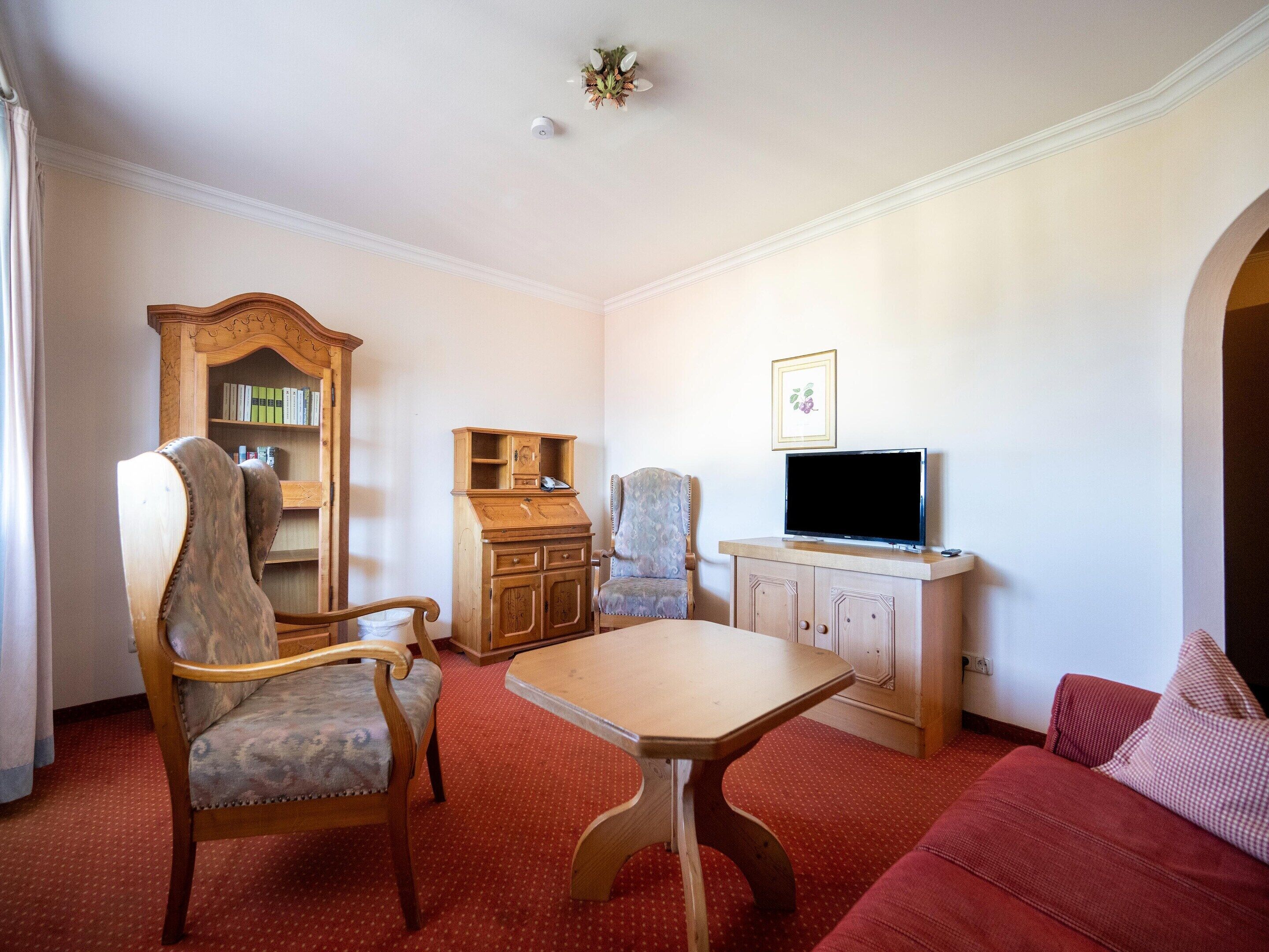 A living room with a wooden cabinet, a television, a sofa, and a chair.
