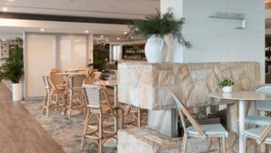 Un restaurant amb cadires de vimet, una paret de pedra i una planta en test.