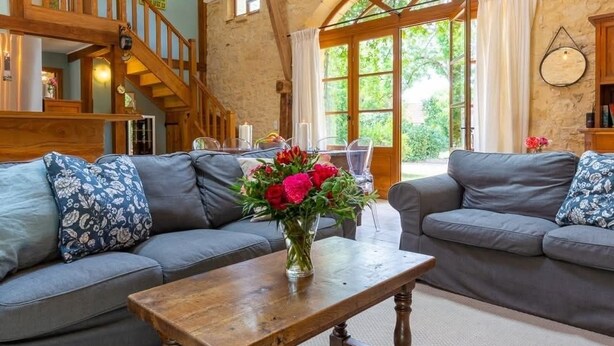 A cozy living room with two grey sofas, a wooden coffee table, and a staircase leading to an upper level. - The Cottage, Les Chouettes, Dordogne Valley where memories are made (Trémolat)