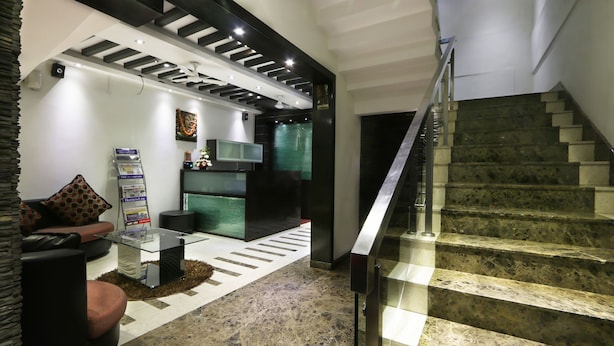 A modern interior with a staircase, a reception area, and a seating area. - Prajwal by Mango Hotels (Bengaluru)