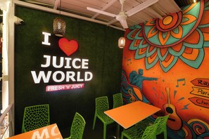 A restaurant interior with a green wall, a mural, and green chairs. - Rayzen Stays (Chennai)