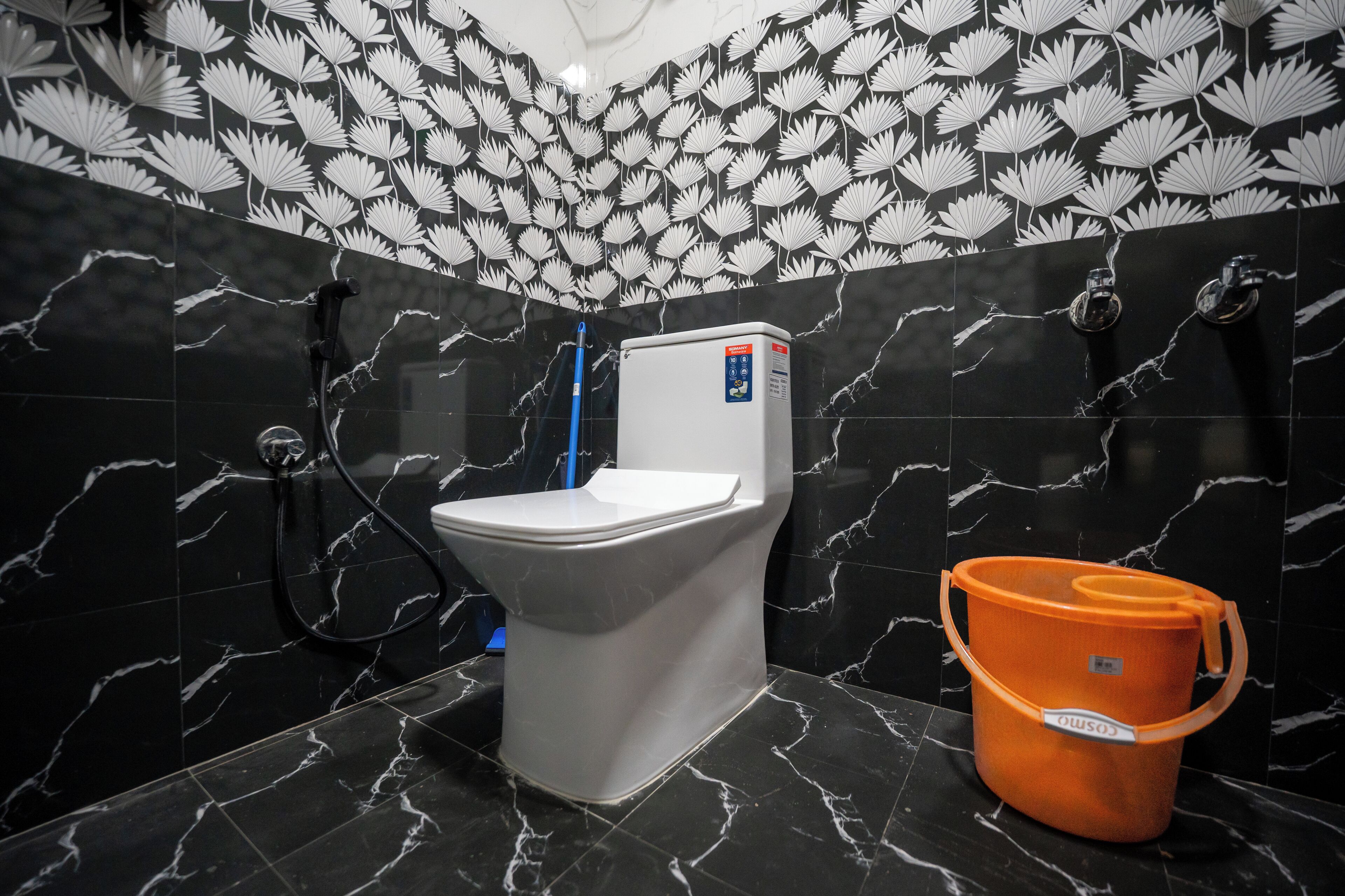 A bathroom with a toilet, a shower, and a bucket.