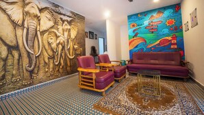 A room with a large elephant mural, a purple sofa, and a patterned floor. - Rayzen Stays (Chennai)