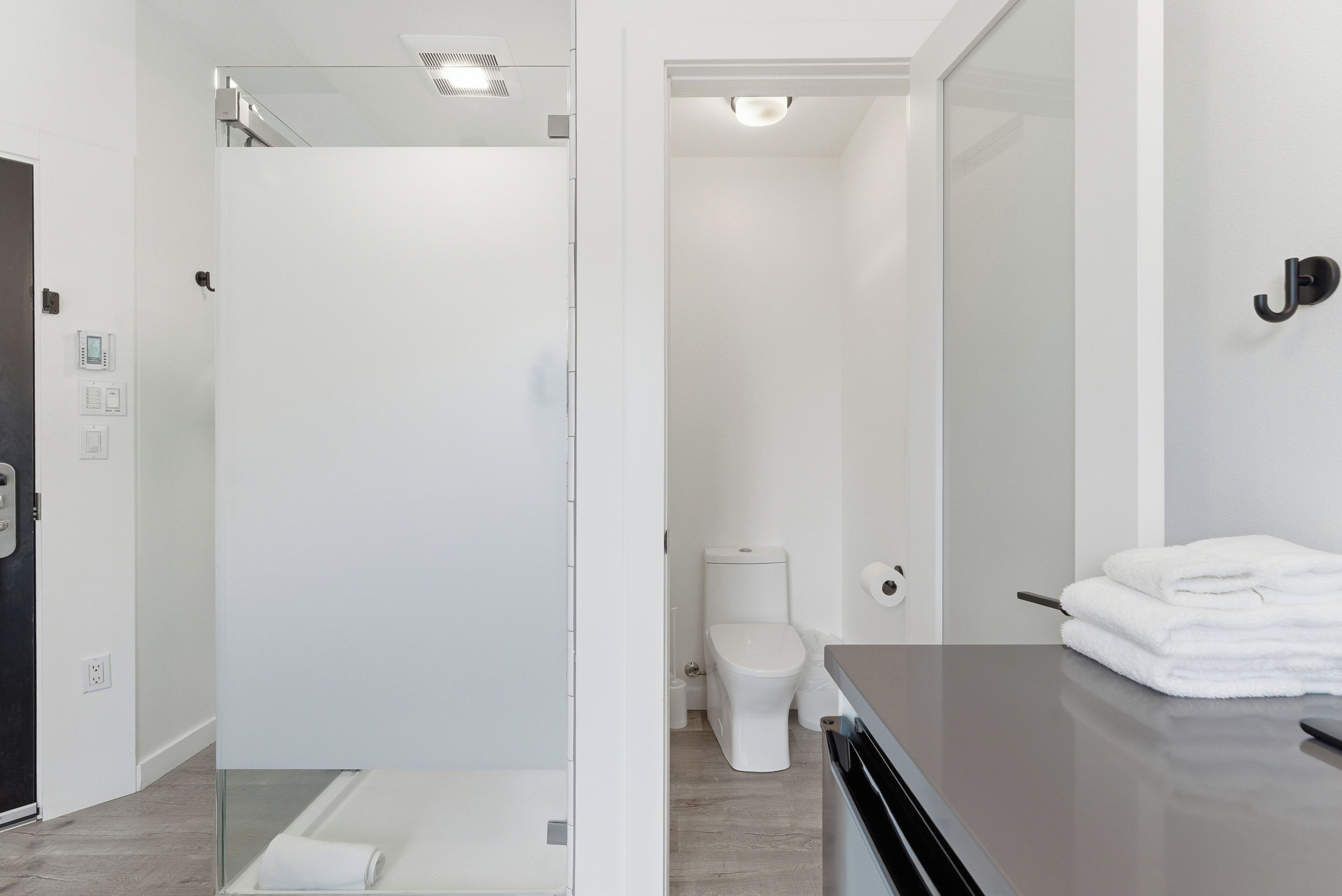 Une salle de bain moderne dotée d’une douche à parois de verre, de toilettes et d’un lavabo avec un porte-serviettes.