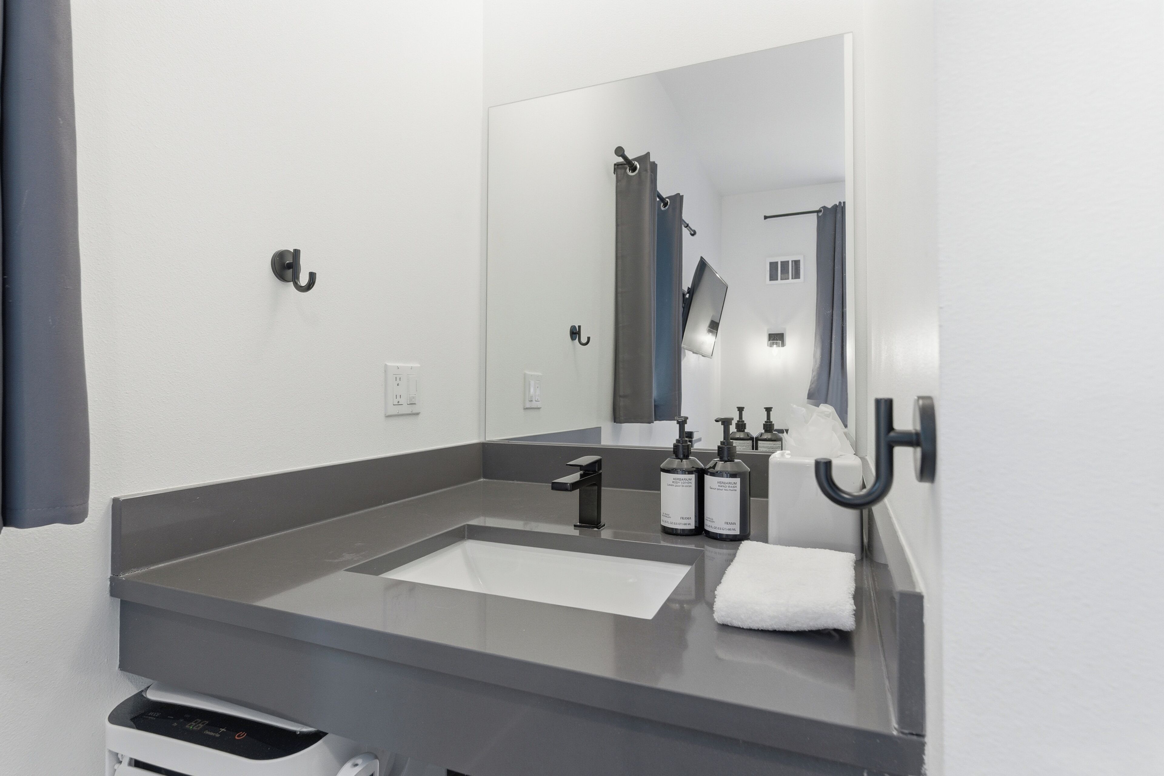 A modern bathroom with a large mirror, a sink, and two bottles of hand soap.