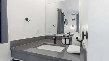 Un baño moderno con un espejo grande, un lavabo y dos botellas de jabón para las manos.
