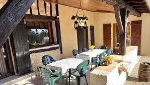 An outdoor patio with a table and chairs, a hanging light fixture, and a rustic stone wall. - 210 m2 villa between nature and bastide in Rives (Rives)