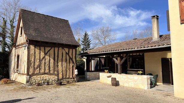 A traditional half-timbered house with a stone foundation and a tiled roof, a stone wall, and a gravel courtyard. - 210 m2 villa between nature and bastide in Rives (Rives)