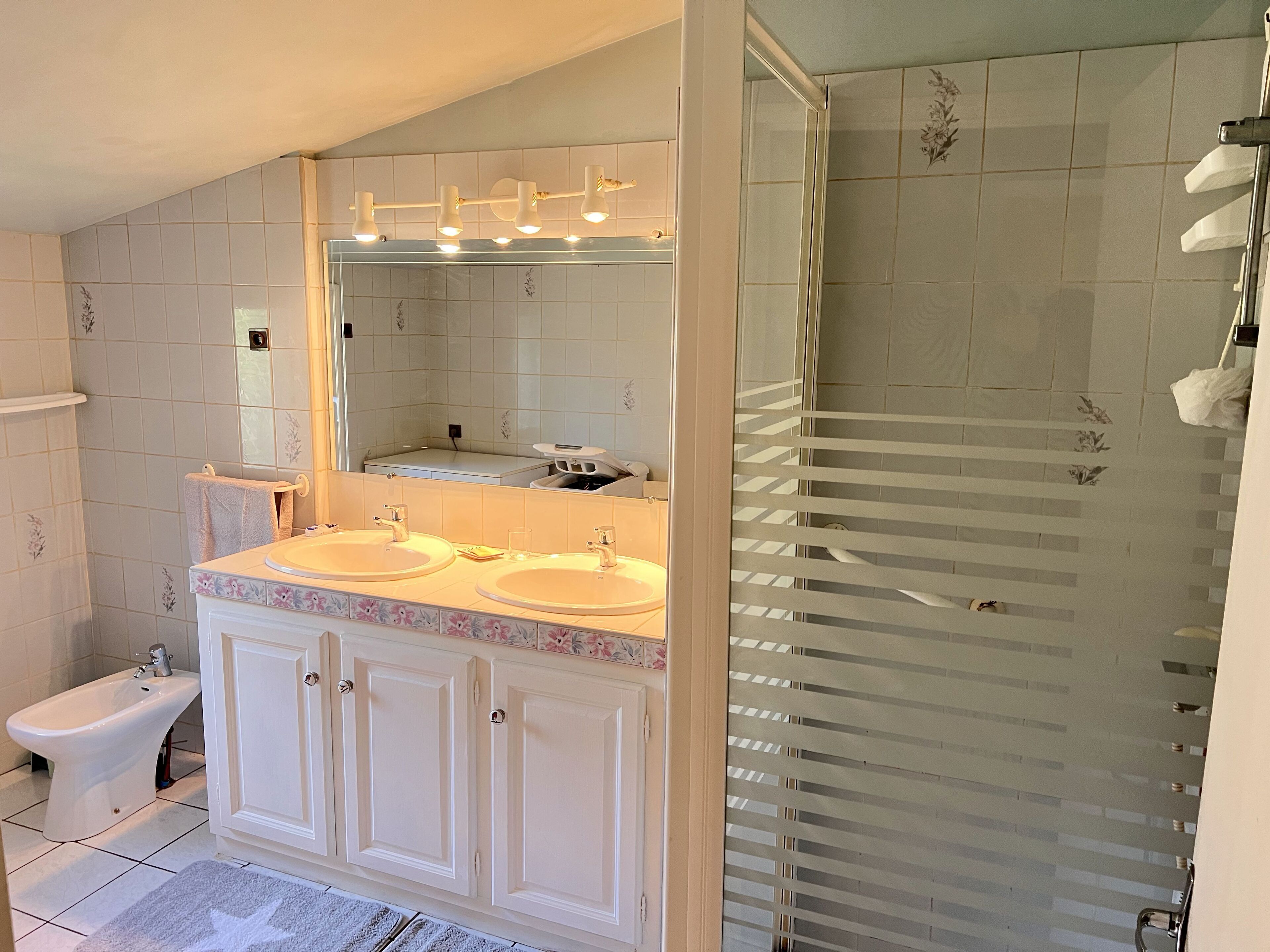 Ein Badezimmer mit zwei Waschbecken, einem Bidet und einer Duschkabine aus Glas.