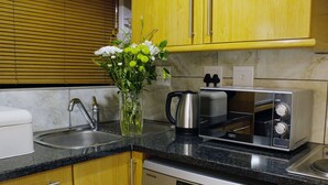 A modern kitchen with yellow cabinets, a stainless steel dishwasher, a microwave, and a coffee maker. - Avemore Eikehof No 2 (Stellenbosch)