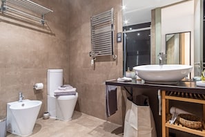 Un baño moderno con un lavamanos grande de color blanco, un inodoro y un bidé.