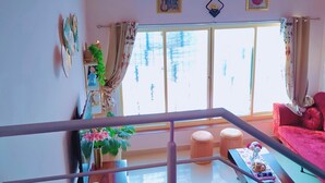 Una sala de estar con un sofá rojo, una mesa de centro y un amplio ventanal con cortinas.