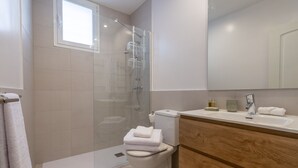 A modern bathroom with a glass-enclosed shower, a toilet, and a vanity with a mirror. - Bright 2-Bed Apartment in Las Letras, Madrid (Madrid)