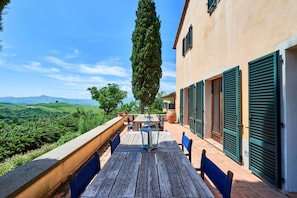 A terrace with a table and chairs, overlooking a scenic landscape.