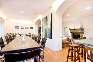 A conference room with a long table and chairs, a fireplace, and a painting on the wall.