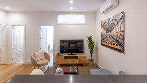 Una sala de estar moderna con un televisor de pantalla plana, un sillón cómodo, una mesita de centro y una estantería.
