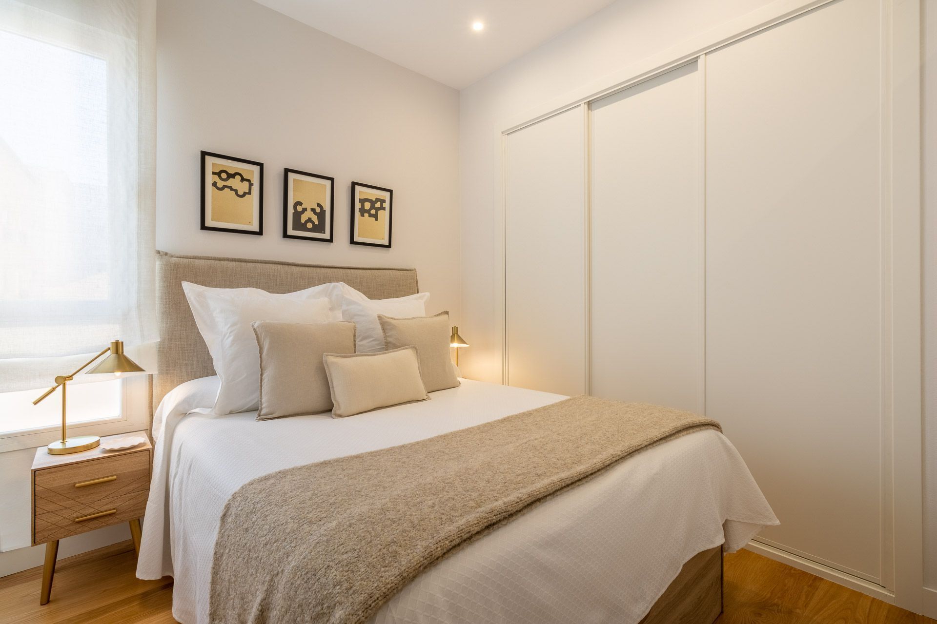Un dormitorio ordenado con cama, mesitas de noche y un armario.