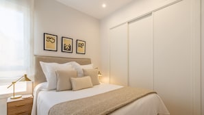 Un dormitorio ordenado con cama, mesitas de noche y un armario.